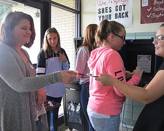 Neighbors | Alexis Bartolomucci.Elizabeth Amstutz handed a voter a pencil and an "I love voting" sticker after she voted in the mock election on Nov. 1 at Glenwood Junior High.