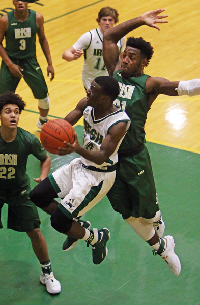 Ursuline's Dakota Hobbs (14) goes up for a layup while being defended by Akron St. Vincent-St. Mary's Justin Sampson (21) during the first half of Friday nights matchup at Ursuline High School in Youngstown.   Dustin Livesay  |  The Vindicator