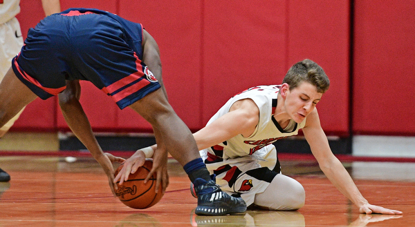 CANFIELD, OHIO - DECEMBER 12, 2016: Ethan Kalina #12 of Canfield attempts to rip the ball from the grasp of Jakari Lumsden #24 of Fitch after Lumsen lost control of the ball during the second half of their game Tuesday night at Canfield High School. DAVID DERMER | THE VINDICATOR