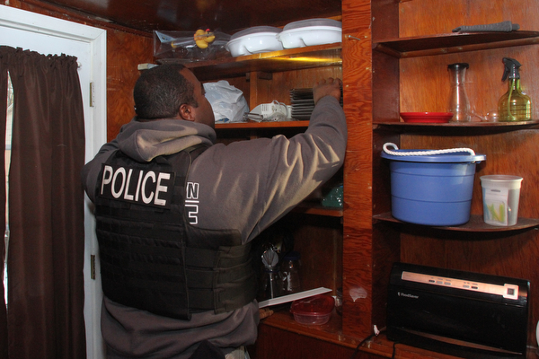 A Youngstown Police officer searches a cabinet after Police and Animal Charities Humane Agents served a search warrant at a house on the 2100 block of Ives St. in Youngstown on Thursday, Dec. 10, 2016...(Nikos Frazier | The Vindicator)..