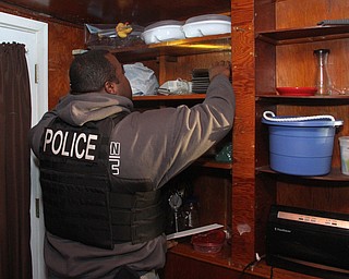 A Youngstown Police officer searches a cabinet after Police and Animal Charities Humane Agents served a search warrant at a house on the 2100 block of Ives St. in Youngstown on Thursday, Dec. 10, 2016...(Nikos Frazier | The Vindicator)..