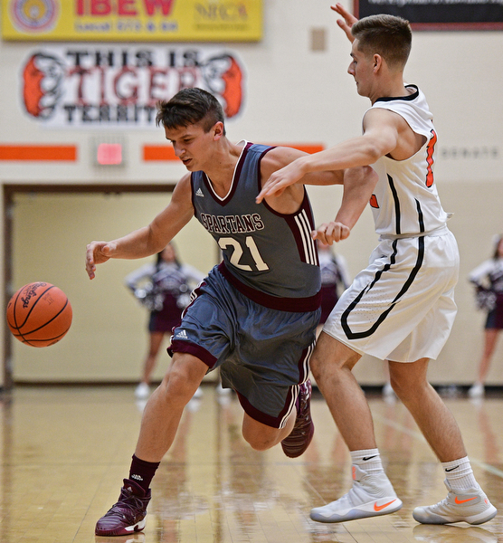 HOWLAND, OHIO - DECEMBER 23, 2016: Sebastian Heineken #21 of Boardman loses control of the ball while being fouled by Michael Missaucci #12 of Howland during the first half of their game Friday night at Howland High School. DAVID DERMER | THE VINDICATOR