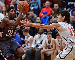 HOWLAND, OHIO - DECEMBER 23, 2016: Che Trevena #32 of Boardman moves the ball above the outstretched arm of Jonah Weisman #11 of Howland while driving to the basket during the first half of their game Friday night at Howland High School. DAVID DERMER | THE VINDICATOR