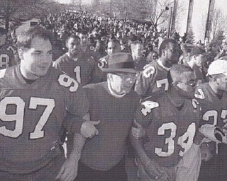 YSU PRESIDENT LES COCHRAN JOUNS ARMS WITH HARRY DELGIANIS(97) AND WILLIS MARSHALL(34) AS THE TEAM LEADS THEIR FANS ONTO VETERANS PLAZA.