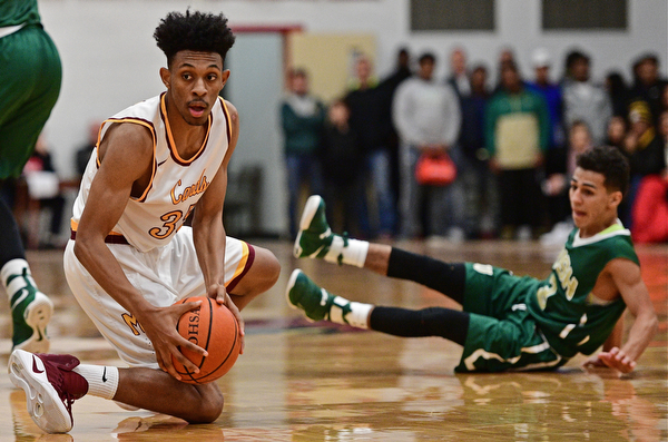 YOUNGSTOWN, OHIO - JANUARY 6, 2016: Jordan Stanford #35 of Ursuline looks to pass the ball after wrestling it away from Anise Algahmee #3 of Ursuline during the first half of their game Friday night at Cardinal Mooney High School. DAVID DERMER | THE VINDICATOR.