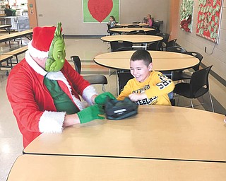 SPECIAL TO THE VINDICATOR: Damascus Elementary School students earned a visit from Cindy Lou Who and the Grinch by raising more than $2,000 in a Penny Wars competition. Money collected from Penny Wars will be used to help families in need in the community. Family Dollar in Beloit donated treats that were passed out to the children by Cindy Lou Who and the Grinch. Above, second grader Tyler Sprowl sits with the Grinch during lunch.