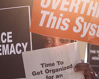 Nikos Frazier | The Vindicator..A protestor shields her face while walking down Euclid Ave.