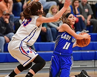 BERLIN CENTER, OHIO - JANUARY 19, 2017: Ashley Totani #11 of Jackson-Milton looks to pass the ball from her knees after forcing Erica DeZee #13 of Western Reserve to turn the ball over during the first half of their game Thursday night at Western Reserve High School. DAVID DERMER | THE VINDICATOR
