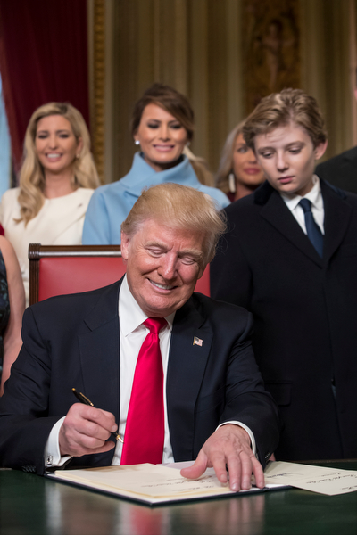 President Donald Trump, joined by the Congressional leadership and his family, formally signs his cabinet nominations into law, Friday, Jan. 20, 2017, in the President's Room of the Senate on Capitol Hill in Washington Behind him are, from left, daughter Ivanka Trump, his wife Melania Trump, and his son Barron Trump. (AP Photo/J. Scott Applewhite, Pool)