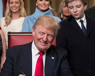 President Donald Trump, joined by the Congressional leadership and his family, formally signs his cabinet nominations into law, Friday, Jan. 20, 2017, in the President's Room of the Senate on Capitol Hill in Washington Behind him are, from left, daughter Ivanka Trump, his wife Melania Trump, and his son Barron Trump. (AP Photo/J. Scott Applewhite, Pool)