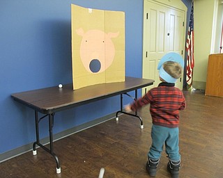 Neighbors | Alexis Bartolomucci.Evan threw a ball through the pig's mouth during the Candy Carnival event at Boardman library on Dec. 28.