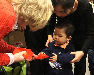 Holly Grant, Pastor Michael Grant's wife, passes out a red envelope to Vier Su(2) and his mom, Susan Hu of Poland during the Chinese New Year Celebration at Poland United Methodist Church in Poland on Sunday, Jan. 29, 2017. ..(Nikos Frazier | The Vindicator)..