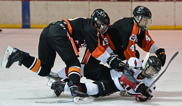 BOARDMAN, OHIO - JANUARY 29, 2017: Robbie Stanko #4 of Canfield is knocked to the ice by Cameron Lucas #4 and Andrew Davidson #19 of Chagrin Falls after he attempted to split the defense during the second period of their game Sunday afternoon at the Ice Zone. DAVID DERMER | THE VINDICATOR
