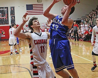 Poland's Brandon Barringer (13) goes up for a layup while being defended by Canfield's Spencer Woolley (11) during Friday nights matchup at Canfield High School.  Dustin Livesay  |  The Vindicator  2/17/17 Canfield High School.
