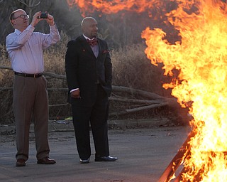 Youngstown Mayor John McNally(D-Youngstown)(left) takes a photo with his phone of the bonfire while standing next to Rev. Jeffrey Stanford of Beulah Baptist church in Youngstown during the Youngstown Peace Walk and Bonfire under the Market St. Bridge in downtown Youngstown, Sunday, Feb. 19, 2017. ..(Nikos Frazier | The Vindicator)..