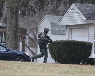        ROBERT K. YOSAY  | THE VINDICATOR..Swat member runs around the neighbors house to get behind the suspects house..GOSHEN Ñ Mahoning County Sheriff Jerry Greene said a suspect is dead from "apparent suicide" after shots were fired as deputies tried to serve a civil order of protection at about 11:20 a.m... .-30-