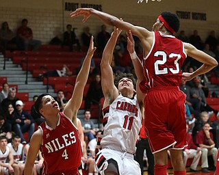 Canfield sophomore forward Spencer Woolley(11) jumps up under the net as Niles sophomore guard Cyler Kane-Johnson(4) and senior forward SaQwaan McGuire(23) try to block his shot during the 3rd quarter as Niles McKinley takes on Canfield, Tuesday, Feb. 28, 2017 at Canfield High School. Canfield won 70-42...(Nikos Frazier | The Vindicator)..