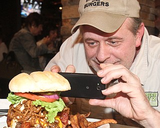William D. Lewis The Vindicator  Burger Guy JT Tranovich gets into his work while photographing a Chipotle Ranch Burger at  Phoenix Fire Grill in Canfield.