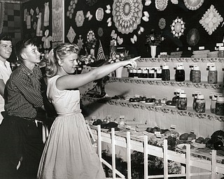 Young people look over the fancy exhibts of Smith Grange at the 1958 Canfield Fair. Names are (left to right) Bruce and Fred Penrod and Maridell Heestand of Sebring