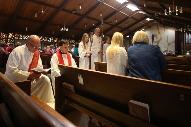 Fr. Michael Swierz kneels at the tenth station of the cross as Casey(center) and Diane Manion follow along in the service book during the Good Friday Stations of the Cross at St. Patrick Church, Friday, April 14, 2017 in Hubbard. ..(Nikos Frazier | The Vindicator)..