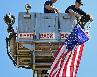 YOUNGSTOWN, OHIO - APRIL 23, 2017: Youngstown firemen Ryan Cook, right, and Eric Swanson, left, work on unveiling the American flag for the national anthem during the Mill Creek Junior Baseball opening ceremonies, Sunday afternoon at the Mill Creek baseball field complex. DAVID DERMER | THE VINDICATOR
