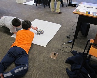 Neighbors | Alexis Bartolomucci.Children checked to see if their Lego Mindstorms Robots followed the track they drew out after they programmed it at the Poland library on March 29.