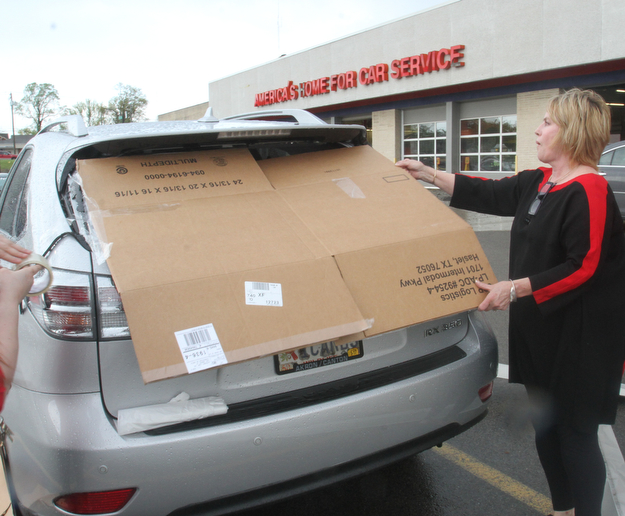 william d Lewis the vindicator Mary Beth Gresko of Salem fits a piece of cardboard over the rear window of her vehicle in hte parking lot of the Southern PArk Mall. A fast moving storm packing strong winds and heavy rain tore part of the roof off the Firtestone Store at the Southern Park Mall Sunday April 30, 1017. Several nearby cars were damagd by debris from  the roof.