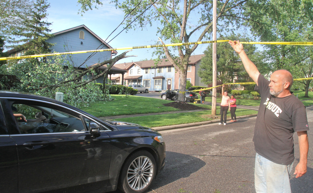 william d Lewis the vindicator A fast movinf storm packing strong winds and heavy rain felled trees and power lines Sunday April 30, 1017. Boardm,an resident Tim Gonda holds up caution tape so a motorist could pass through Applecrest Circle in Boardman.