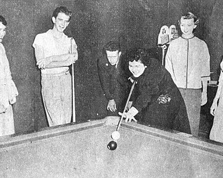 Vindicator file photo | May 16, 1954A good deal of the credit for the exceptionally high morale and fine records at the Air Force‚Äôs jet air base at the Youngstown Municipal Airport can go to the Youngstown -Mahoning County USO Committee which has gone all out to keep the enllisted men entertained with weekly dances, dinners and other entertainment. Most popular is the junior hostess program sponsored jointly with with YWCA and and the recent dance brought out the enlisted men in droves to dance with pretty girls, watch a floor show and enjoy a midnight snack. Above,  Joan Lind tries a pool shot under the watchful eyes of Peg Repasky, A2C Don Bedwell, A3C Jake Cater, Mary Lentine and Betty Conroy.