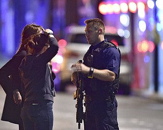 An armed Policeman talks to members of the public outside London Bridge Hospital as police are dealing with an incident on London Bridge in London, Saturday, June 3, 2017. Witnesses reported a vehicle hitting pedestrians and injured people on the ground. (Dominic Lipinski/PA via AP)