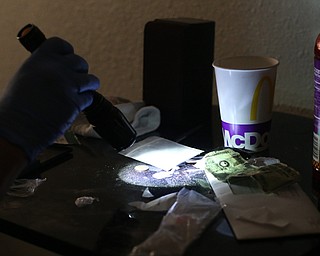 A police officer shines a flashlight onto a bag of Fentanyl found open on a bookshelf as Youngstown Police search a house on the 200 block of E Judson Ave, Thursday, June 1, 2017 in Youngstown. The bag was sampled and field tested on scene...(Nikos Frazier | The Vindicator)
