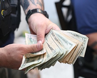 A police officer fans out a stack of money as it is counted and bagged as evidence as Youngstown Police search a house on the 200 block of E Judson Ave, Thursday, June 1, 2017 in Youngstown...(Nikos Frazier | The Vindicator)