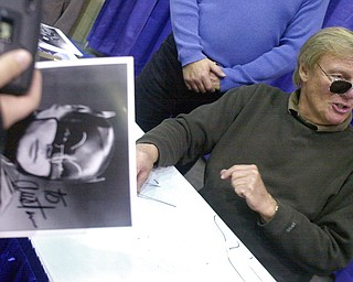 FILE - In this Feb. 23, 2002 file photo, a fan holds a signed photograph of actor Adam West, right, during the 50th Autorama in Detroit. On Saturday, June 10, 2017, his family said the actor, who portrayed Batman in a 1960s TV series, has died at age 88. (AP Photo/Paul Warner, File)