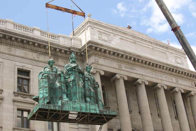     ROBERT K. YOSAY  | THE VINDICATOR..the newly-restored copper statues were returned to its roof of the courthouse..The statues, removed in October 2010, have been returned to their perch above the courthouse's main entrance where they had sat since 1909...The three hollow statues, which were restored by an Oberlin firm, are named ÒJustice,Ó on the left, ÒStrength and AuthorityÓ in the center; and ÒLawÓ on the right.