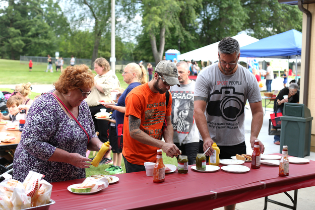 (from left) Alma Cummins, Ray Metz and Drew Graham add condiments to their hot dogs during the 19th annual Struthers Day at Mauthe Park, Thursday, June 29, 2017 in Struthers...(Nikos Frazier | The Vindicator)