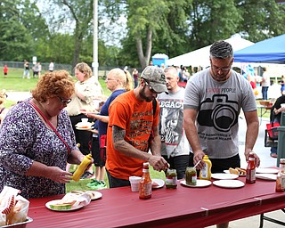 (from left) Alma Cummins, Ray Metz and Drew Graham add condiments to their hot dogs during the 19th annual Struthers Day at Mauthe Park, Thursday, June 29, 2017 in Struthers...(Nikos Frazier | The Vindicator)