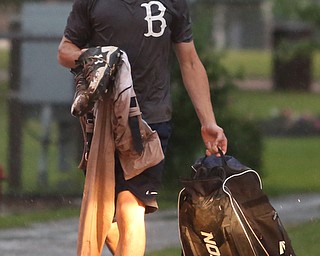 Baird catcher Coleman Stauffer(20) walks through the rainy parking lot after play was stopped in the 6th inning due to a lightning delay then never resumed because of heavy rain during a Class B baseball game between Roth Brothers and on Baird Brothers, Friday, June 30, 2017 at Bob Cene Park...(Nikos Frazier | The Vindicator)..