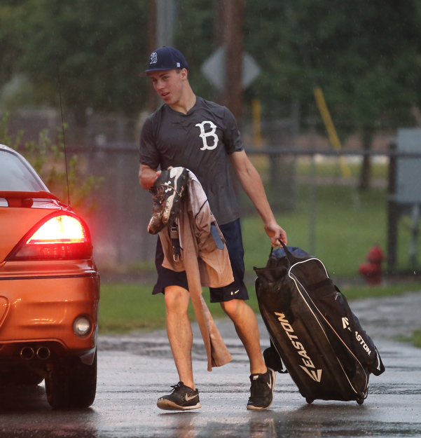 Baird catcher Coleman Stauffer(20) walks through the rainy parking lot after play was stopped in the 6th inning due to a lightning delay then never resumed because of heavy rain during a Class B baseball game between Roth Brothers and on Baird Brothers, Friday, June 30, 2017 at Bob Cene Park...(Nikos Frazier | The Vindicator)..