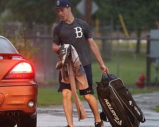 Baird catcher Coleman Stauffer(20) walks through the rainy parking lot after play was stopped in the 6th inning due to a lightning delay then never resumed because of heavy rain during a Class B baseball game between Roth Brothers and on Baird Brothers, Friday, June 30, 2017 at Bob Cene Park...(Nikos Frazier | The Vindicator)..