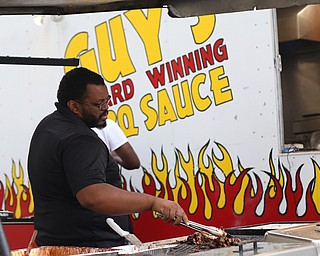 Sean Hughes, the everything man at Guy's Award Winning BBQ Sauce, BBQ's some pulled pork before the Fabulous Flashbacks perform in Central Square, Friday, July 7, 2017 in downtown Youngstown...(Nikos Frazier | The Vindicator)