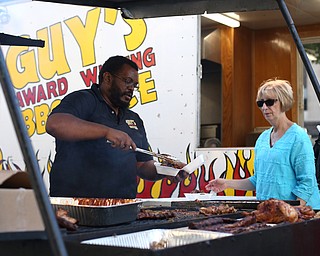 Sean Hughes, the everything man at Guy's Award Winning BBQ Sauce, serves Kathy Rager of West Middlesex, Pa. during the Youngstown Jazz and Wine Fest, Saturday, July 8, 2017 in Central Square in downtown Youngstown...(Nikos Frazier | The Vindicator)