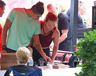 Chris London (left) of Columbus and Lexi Cloud of Youngstown look through pieces shaped from steel at "The Dragon Smith" during the Summer Festival of the Arts at Youngstown State University on Saturday afternoon.  Dustin Livesay  |  The Vindicator  7/8/17  Youngstown State University.