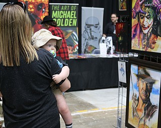  ten month old Camden Barnes of Howland looks over his mothers shoulder at paintings during the All Americon convention at the Covelli Center in Youngstown on Saturday afternoon.  Dustin Livesay  |  The Vindicator  7/8/17  Covelli Center.