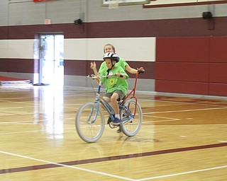 Neighbors | Alexis Bartolomucci.A rider rode his bike around the Boardman Glenwood Middle School gym as one of the volunteers helped him.