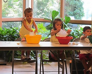 Neighbors | Alexis Bartolomucci.Children poured flour into their mixing bowls as they prepared to make their own play dough after reading a story.
