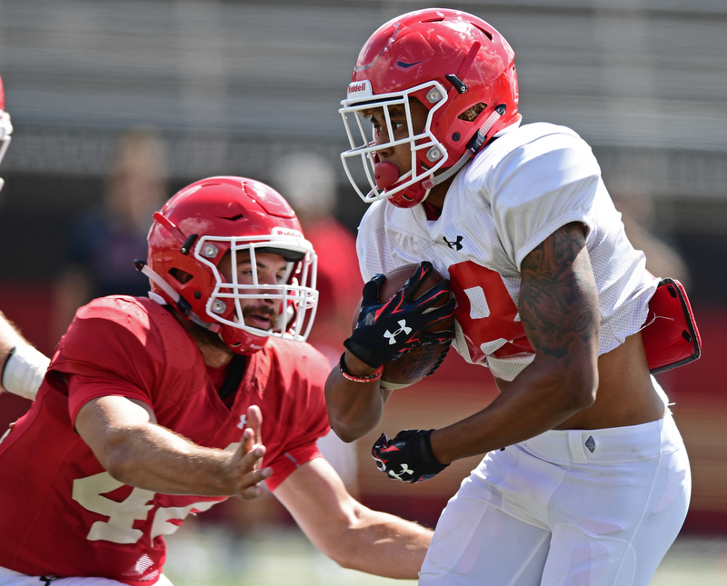 YOUNGSTOWN, OHIO - AUGUST 8, 2017: Youngstown State's London Pearson, white, runs the football away from Armand Dellovade, red, during the teams practice Tuesday morning at Stambaugh Stadium. DAVID DERMER | THE VINDICATOR