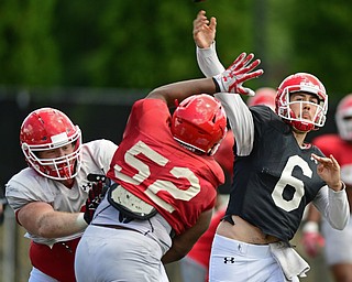 YOUNGSTOWN, OHIO - AUGUST 8, 2017: Youngstown State's Hunter Wells throws a pass from the pocket behind a block from his offensive line on Savon Smith, red, during the teams practice Tuesday morning at Stambaugh Stadium. DAVID DERMER | THE VINDICATOR