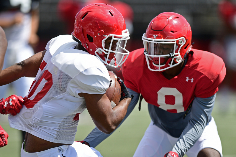 YOUNGSTOWN, OHIO - AUGUST 8, 2017: Youngstown State's Christian Turner, white, runs the ball before being hit by D.J. Thomas, red, during the teams practice Tuesday morning at Stambaugh Stadium. DAVID DERMER | THE VINDICATOR