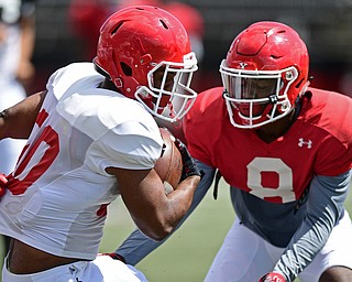 YOUNGSTOWN, OHIO - AUGUST 8, 2017: Youngstown State's Christian Turner, white, runs the ball before being hit by D.J. Thomas, red, during the teams practice Tuesday morning at Stambaugh Stadium. DAVID DERMER | THE VINDICATOR