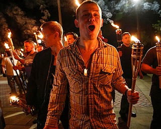 In this photo taken Friday, Aug. 11, 2017, multiple white nationalist groups march with torches through the UVA campus in Charlottesville, Va. Hundreds of people chanted, threw punches, hurled water bottles and unleashed chemical sprays on each other Saturday after violence erupted at a white nationalist rally in Virginia. (Mykal McEldowney/The Indianapolis Star via AP)